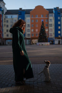 Rear view of woman with dog in city