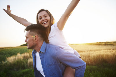 Boyfriend piggybacking girlfriend while standing on land