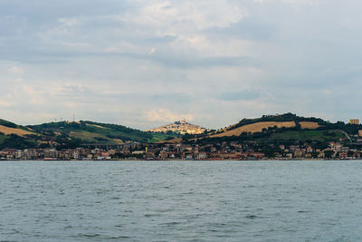 Scenic view of sea by town against sky