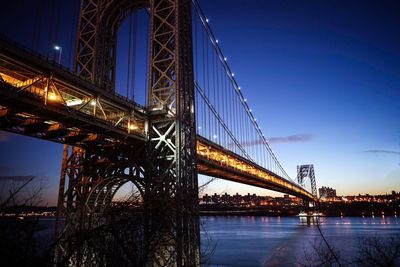 Illuminated george washington bridge over hudson river against sky at dusk