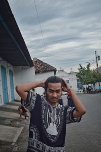 Portrait of young man standing against sky