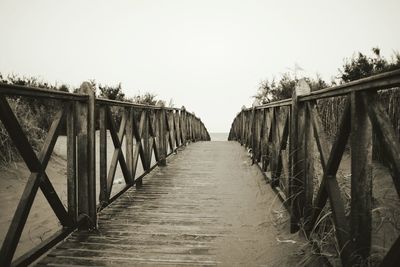 Footbridge amidst trees against clear sky