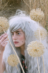 Man in gray wig holding plant in forest