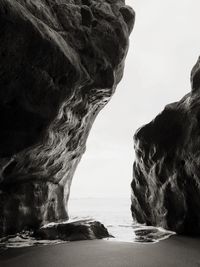 Rock formation on sea shore against sky