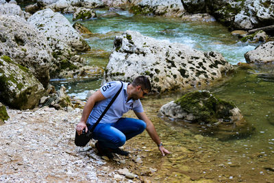 High angle view of woman sitting on rock by river