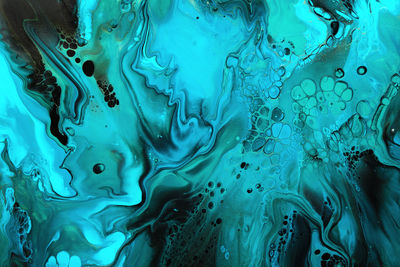 Fluid art. green and blue abstract wave swirls on black background. marble effect background or