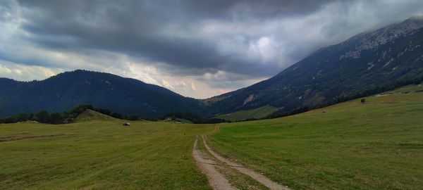 Scenic view of road by mountains against sky