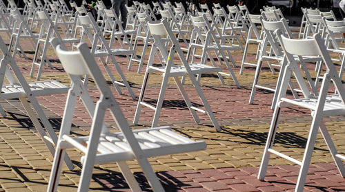 White folding chairs are placed on the square on pavement. quarantine restrictions, mass events