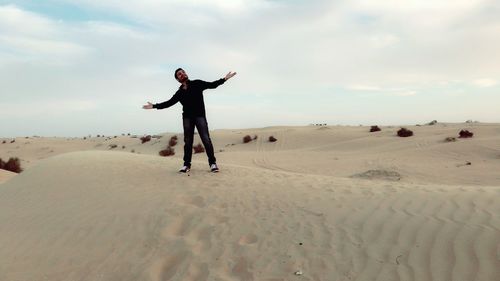 Full length of man with arms raised on beach