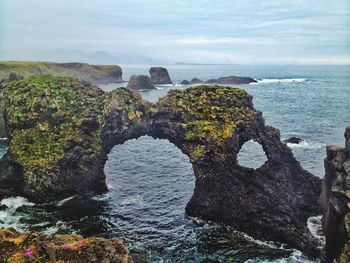 Rock formations by sea against sky