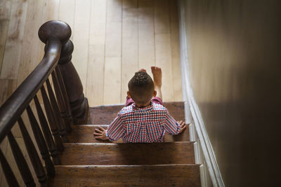 High angle view of boy sitting on stairs at home