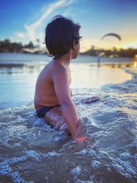 Rear view of shirtless boy in swimming pool against sky