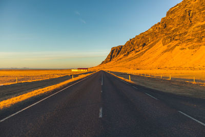 Road amidst landscape against clear sky during sunset