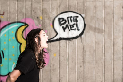 Side view of young woman standing in front of wall