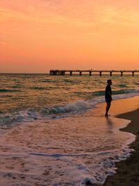 Silhouette person on beach against sky during sunset