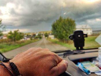 Close-up of hand holding camera against sky