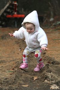 Cute baby girl walking with arms outstretched on land