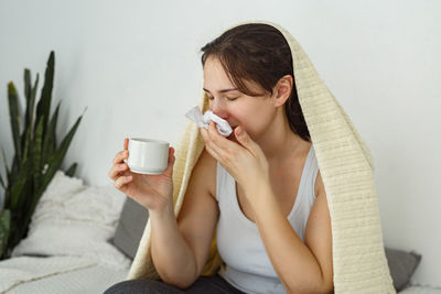 Young woman drinking milk while sitting on bed at home