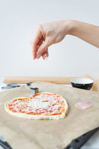 Cropped hand of person holding pizza on table