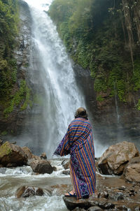 Robed in traditional woven cloth on a waterfall