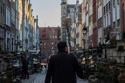 Rear view of man in city against sky