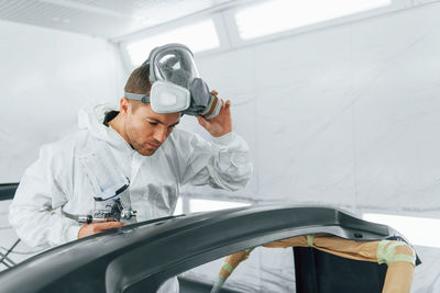 Painting the car. man in uniform is working in the auto service.