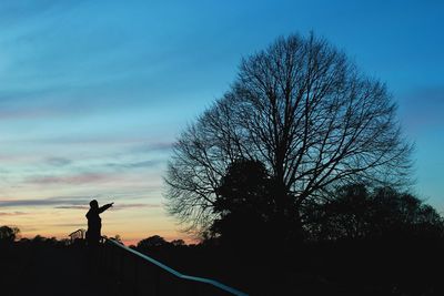 Silhouette man standing on landscape against blue sky