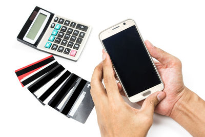 Close-up of hand using mobile phone against white background