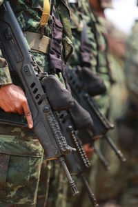 Midsection of army soldiers holding rifles