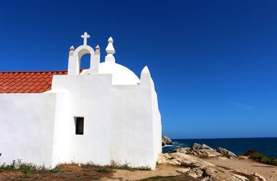 Building by sea against clear blue sky