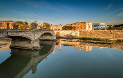 Reflection of ponte vittorio emanuele ii over river