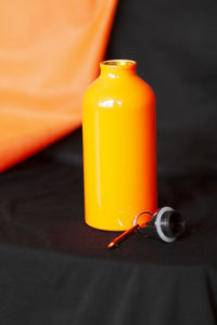 Close-up of orange bottle on table