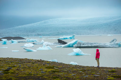 Full length of woman standing on landscape by sea against sky