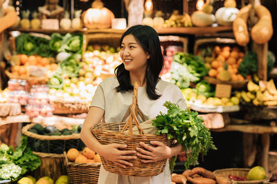 Portrait of young woman with fruits for sale at market