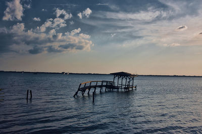 Silhouette pier over sea against sky during sunset