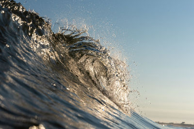 Close-up of water splashing in sea against sky