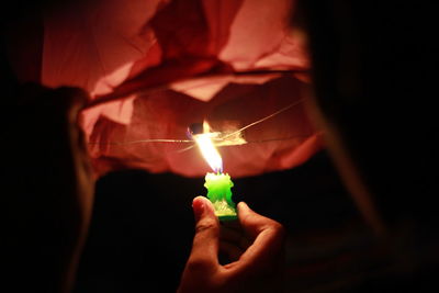 Close-up of hand holding lit candle