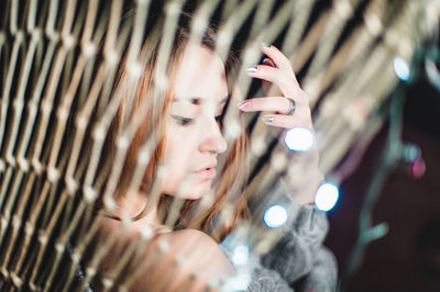 Beautiful woman wearing sweater seen through illuminated netting