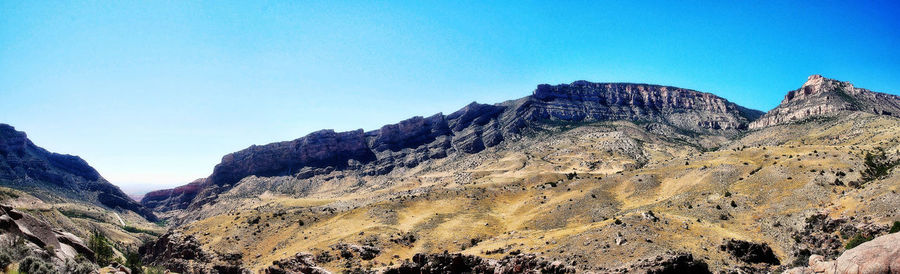 Panoramic view of rocky mountains against clear blue sky