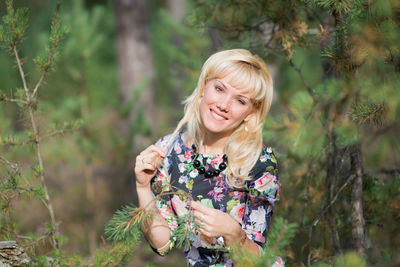 Portrait of young woman holding leaves in forest