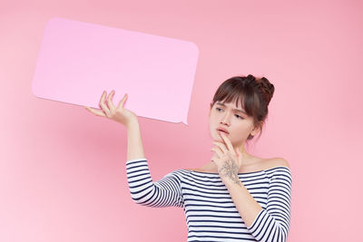 Portrait of woman standing against pink background