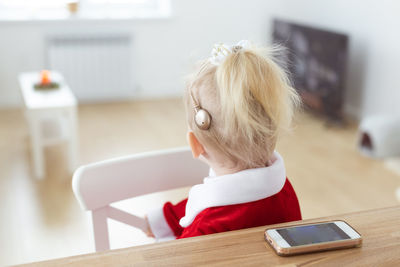 Side view of boy using mobile phone while sitting on chair at home