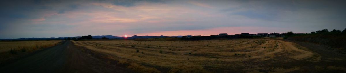 Panoramic view of agricultural field against sky during sunset