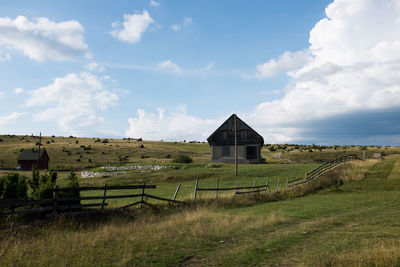 Built structure on grassy field against cloudy sky