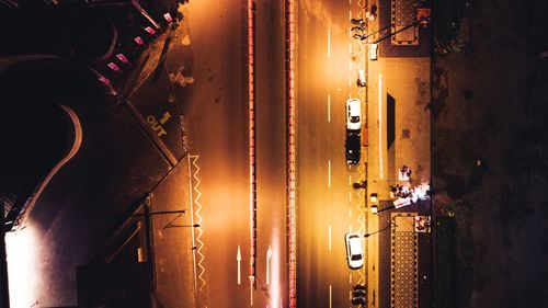 People on illuminated street amidst buildings at night