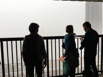 Rear view of people standing on railing