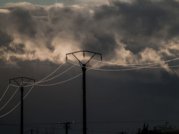 Low angle view of silhouette electricity pylon against sky