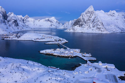 Scenic view of frozen lake by snowcapped mountains against sky