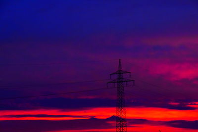 Low angle view of silhouette electricity pylon against dramatic sky