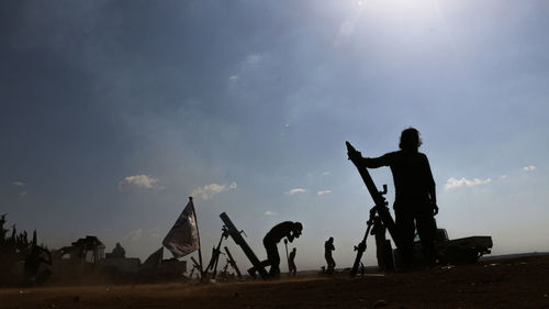 Silhouette people standing on land against sky during sunset